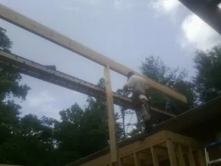 Carpenter setting a ridge beam over a new addition frame — Ice Dam Removal by Roofing Brothers in Penney Farms