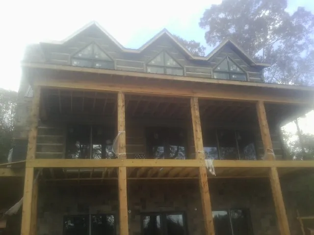 Dormers and porch framing on a large log home under construction — Roof Coating work by our crew in Penney Farms