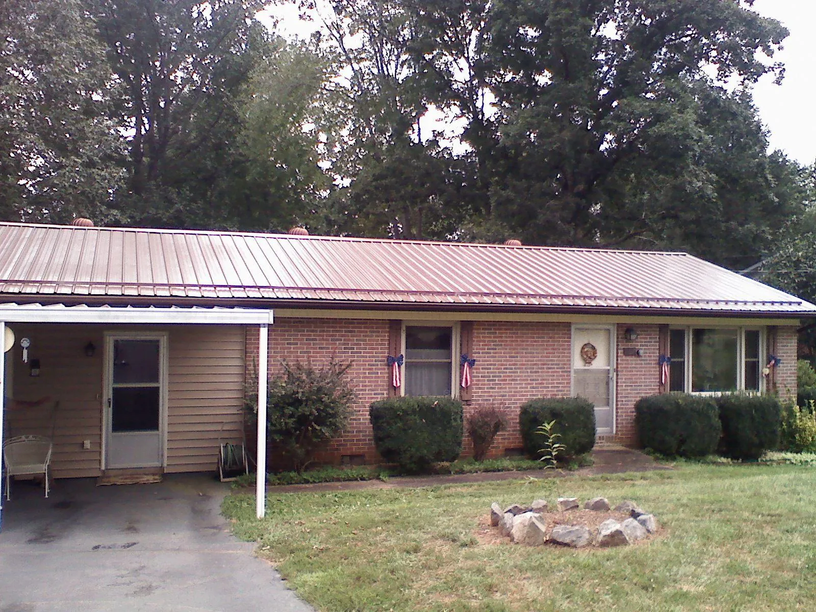 Bronze metal roof and carport on a brick ranch home — Roof Repair work by our crew in Penney Farms