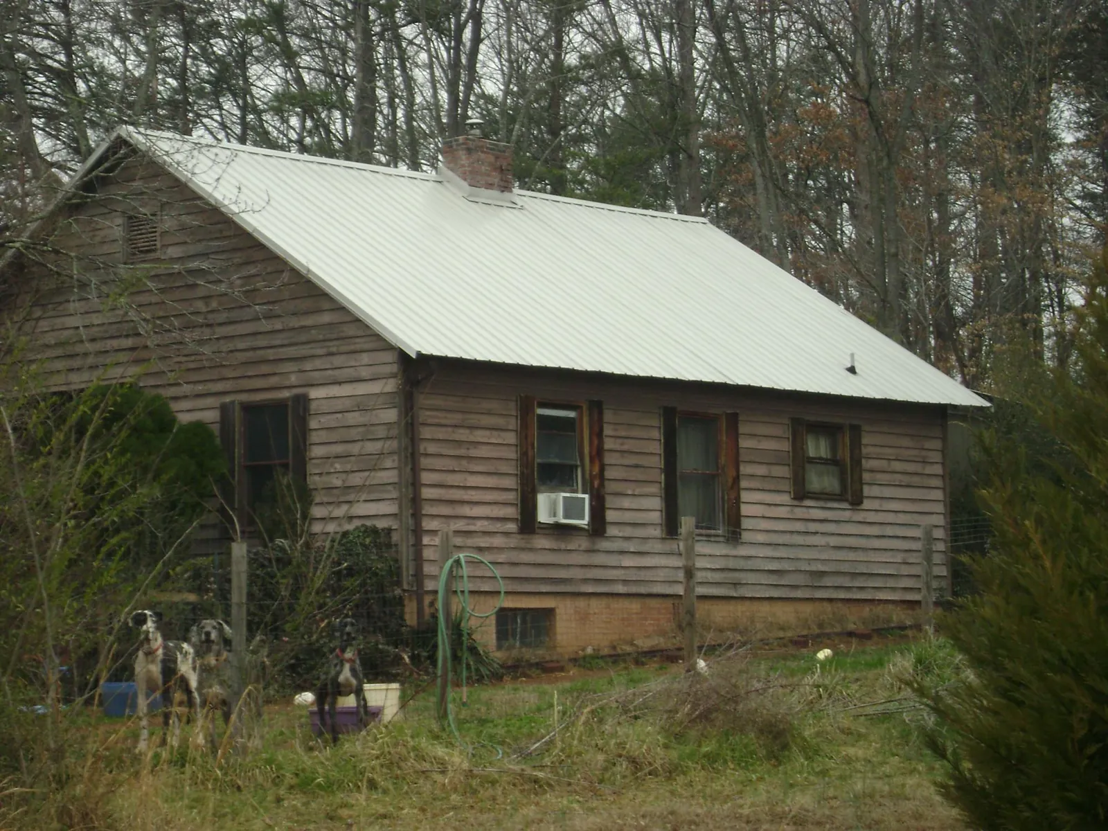 White metal roof on an old wood sided farmhouse, from a Metal Roof Installation job in Penney Farms
