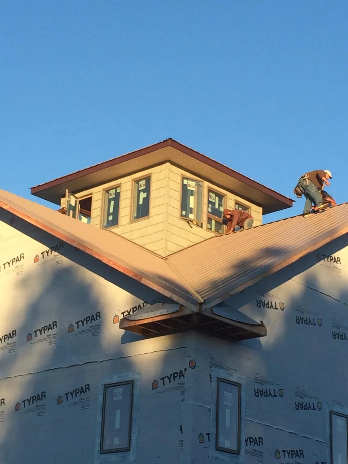 Roofers working around a rooftop cupola on a new metal roof at sunset — Roof Waterproofing in Penney Farms by Roofing Brothers